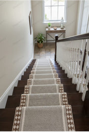 A set of cream and brown woven stair runner rugs with diamond-patterned borders, styled on a dark wood staircase in a bright, modern home interior.